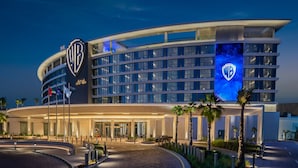 Un hotel moderno con fachada curva, varios pisos y el logotipo destacado de WB.