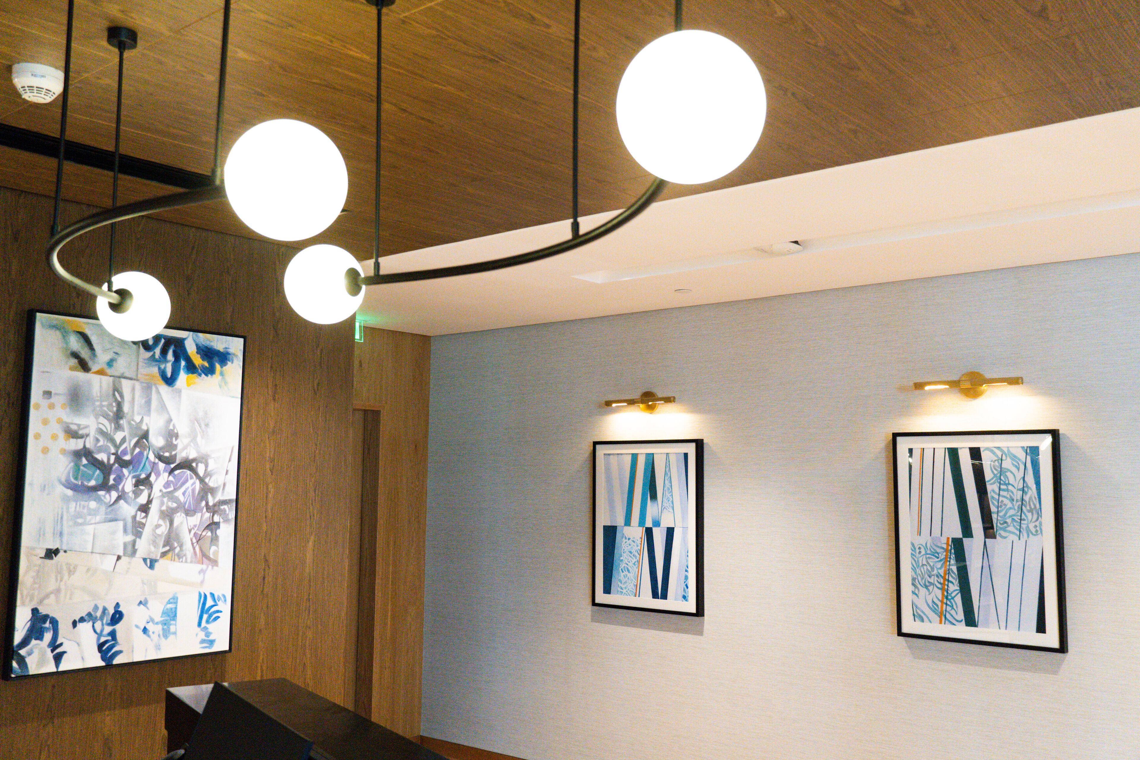 A modern interior with wooden ceiling, pendant lighting, and abstract wall art.