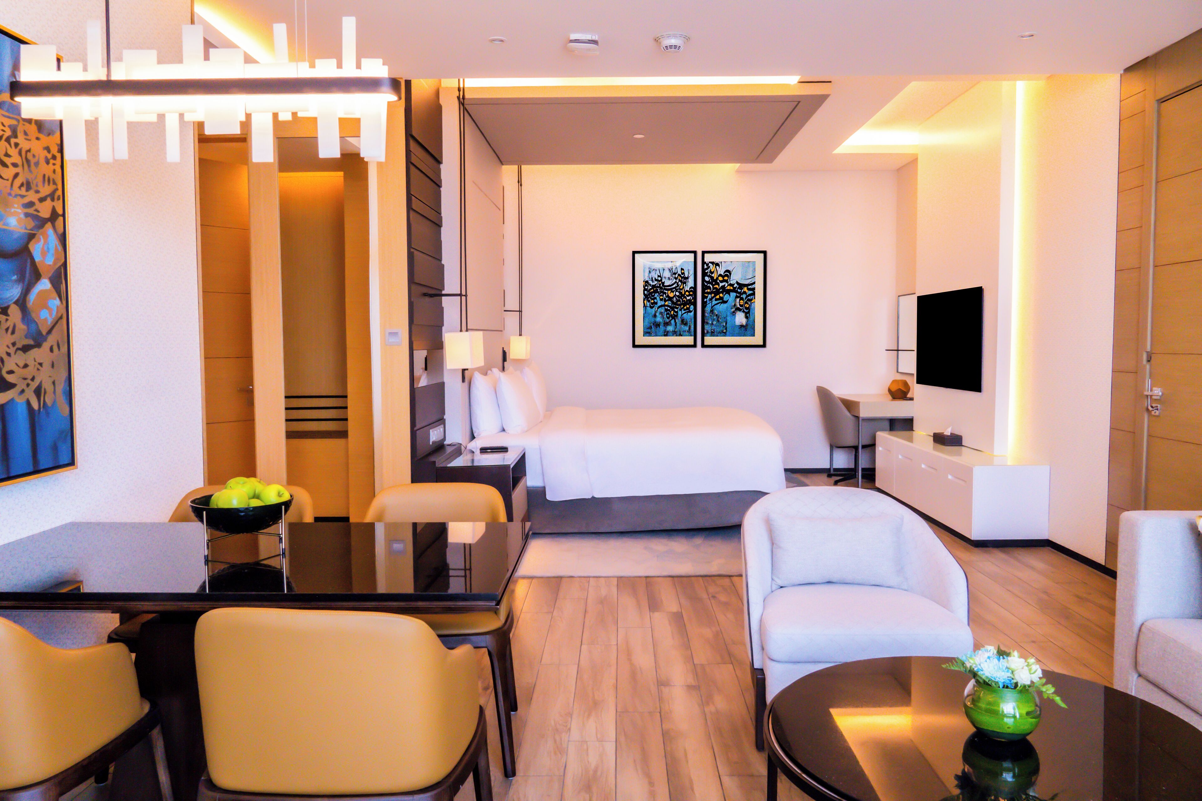 Une chambre d’hôtel moderne équipée d’un lit, d’un bureau, d’une chaise, d’un canapé, d ’une télévision et d’un coin repas avec une table et des chaises.