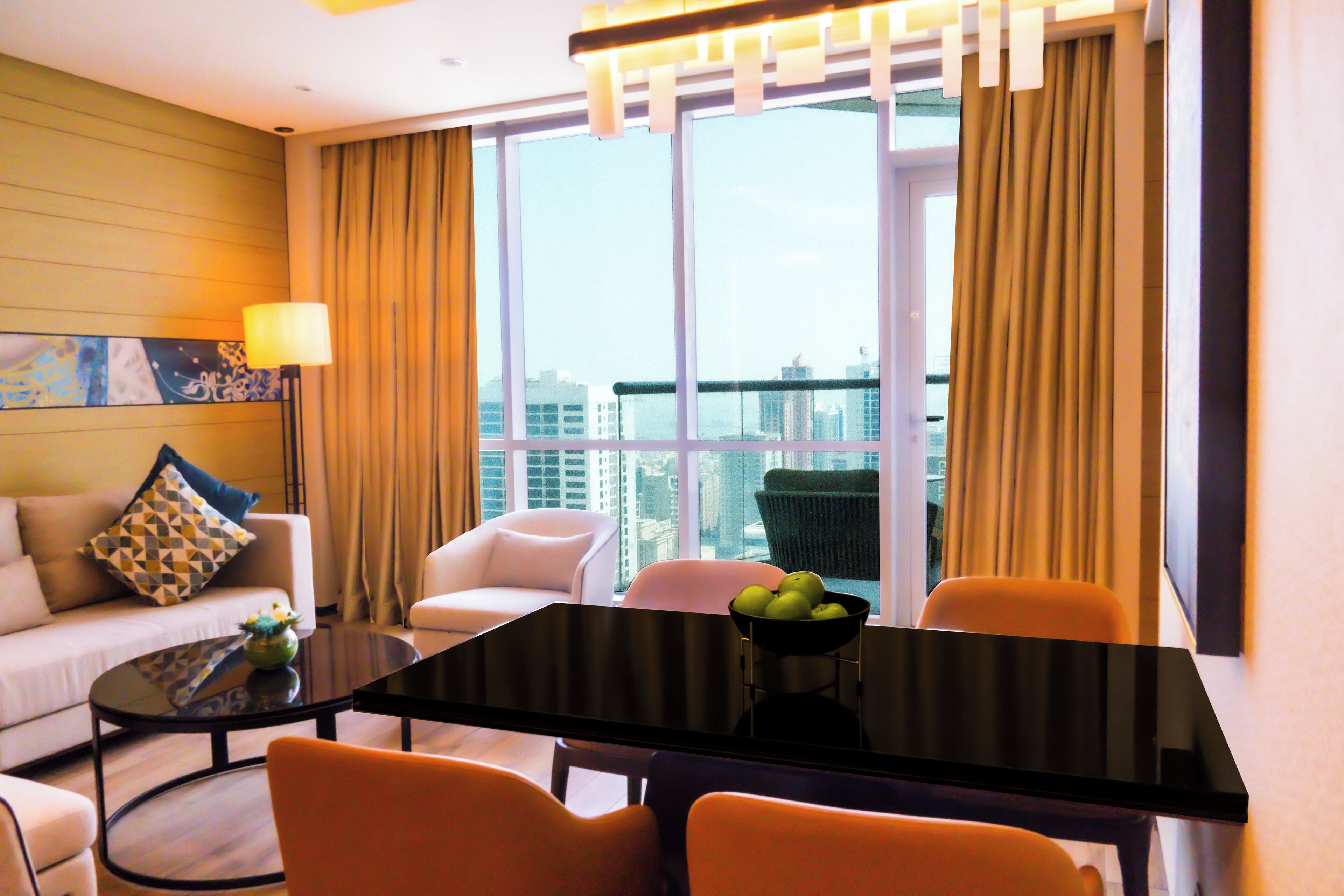 A modern hotel room with a balcony, a dining table, and a sofa.