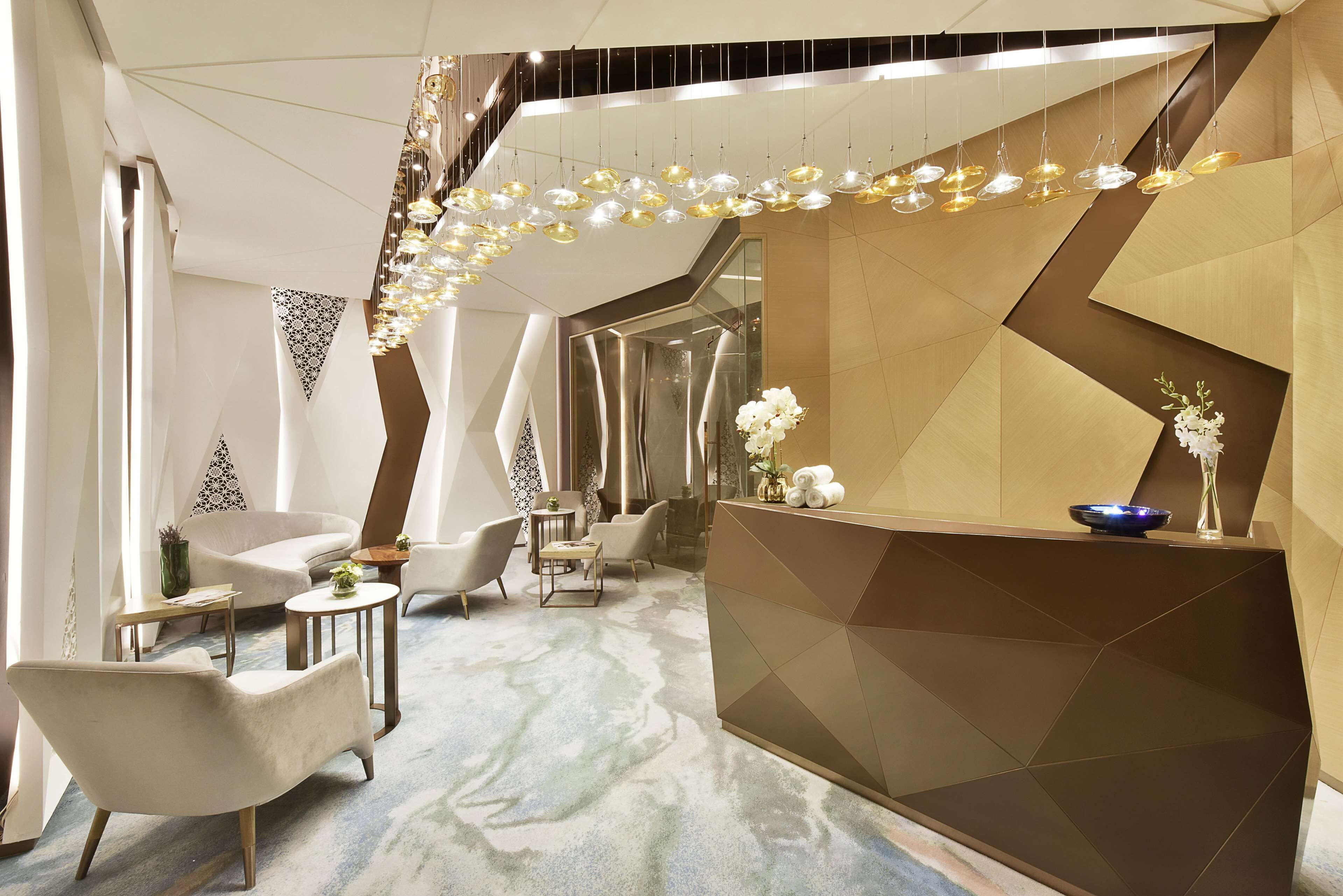 Un espace d’accueil moderne doté d’un comptoir d’accueil aux lignes géométriques, de plusieurs options d’assises et d’un luminaire décoratif.