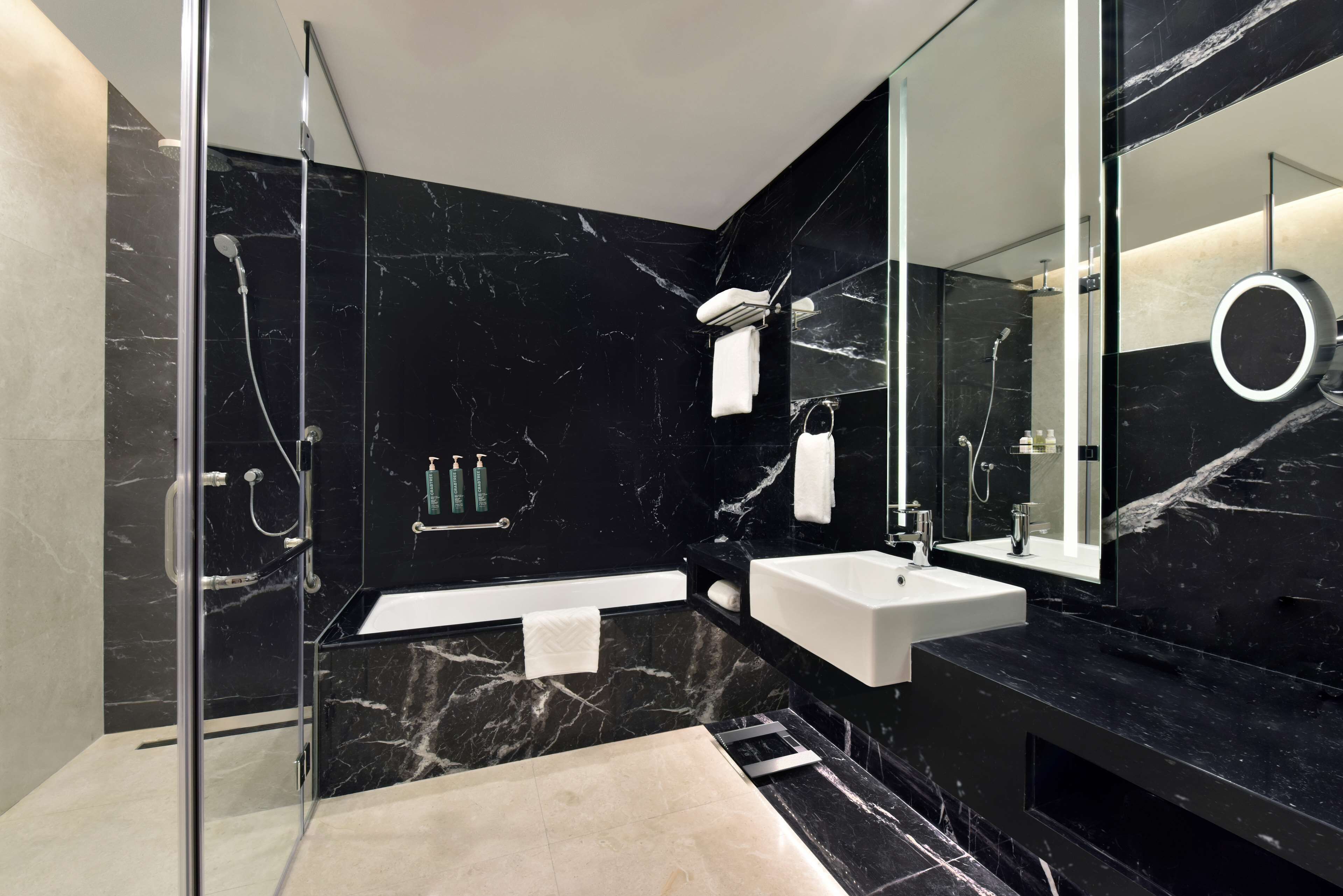 A modern bathroom with a glass-enclosed shower, a white sink, and a large mirror.