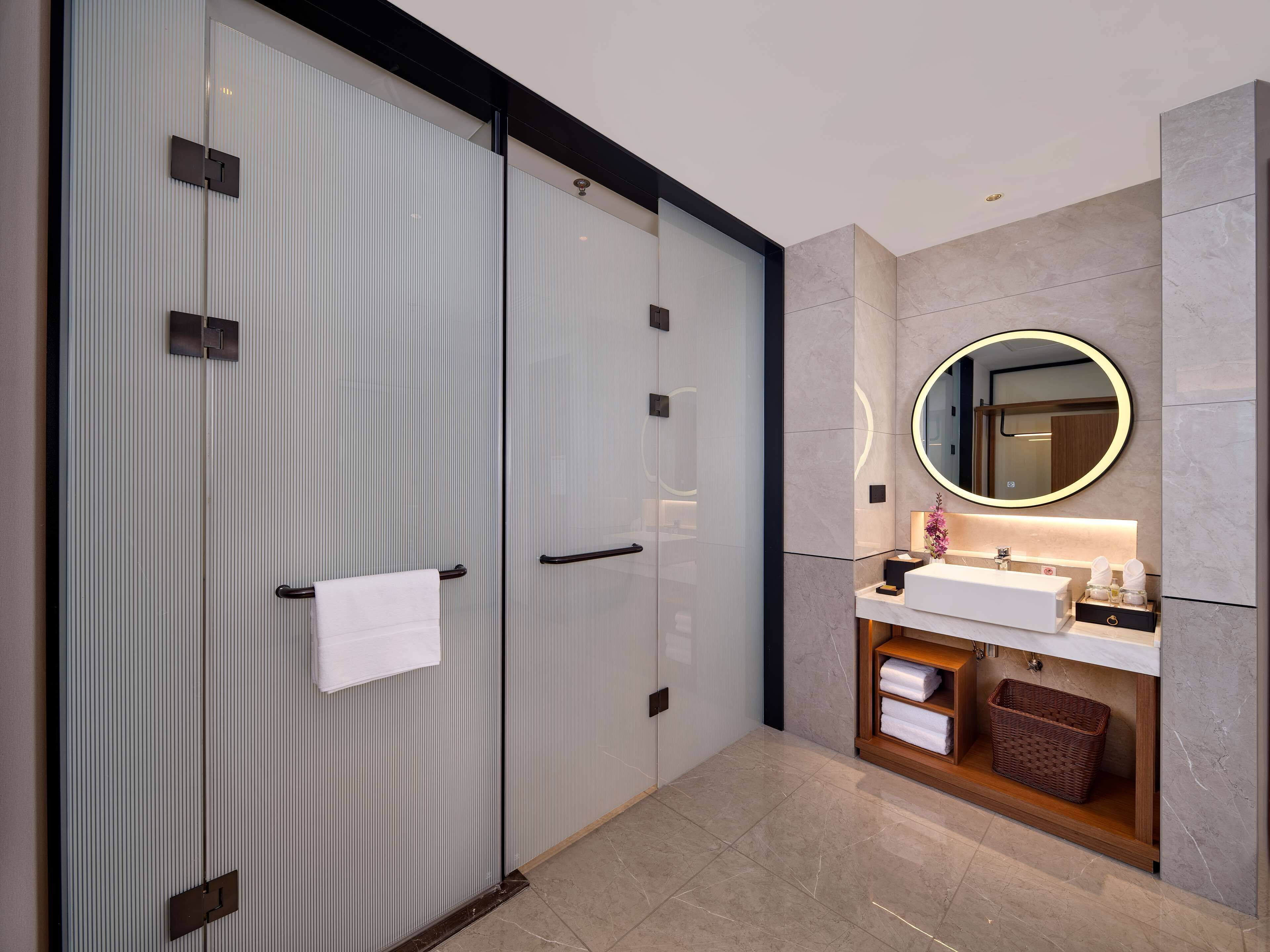 A modern bathroom with a large mirror, a vanity with a sink, and a storage cabinet.
