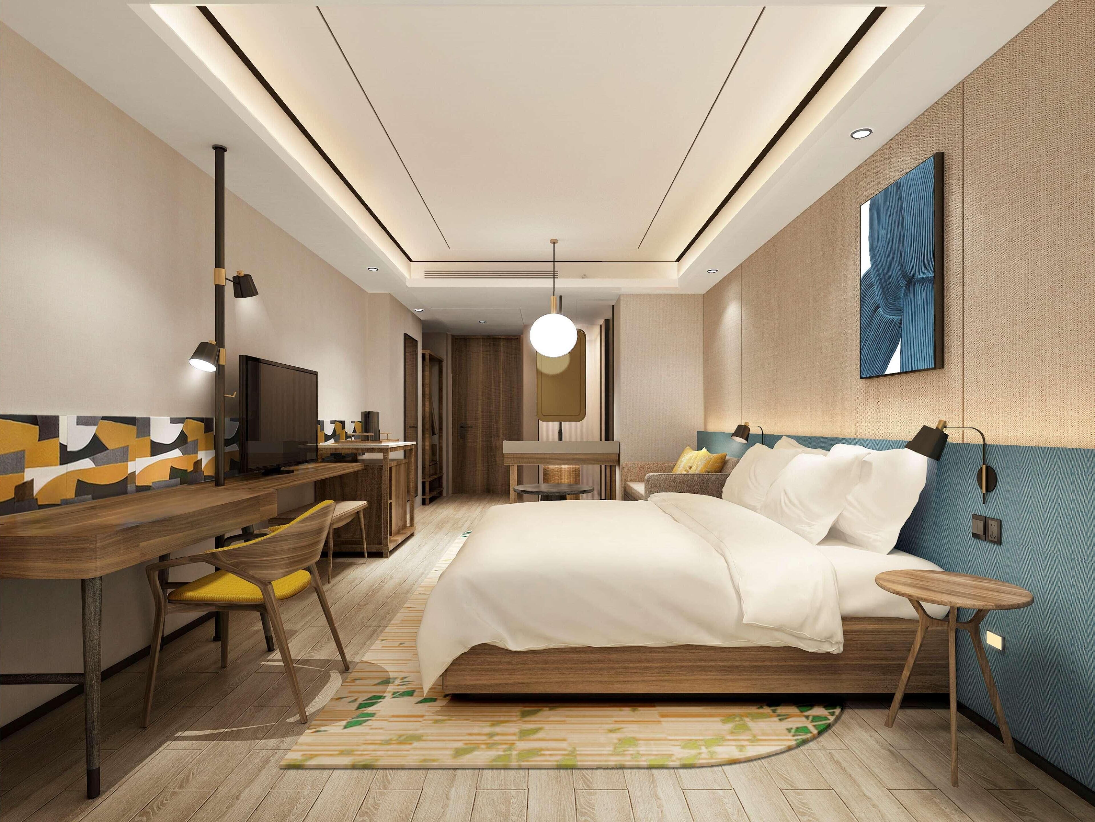 A modern hotel room with a bed, desk, and seating area.