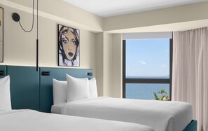 A hotel room with two beds, a large window with a view of the sea, and a painting on the wall. - ROK Hotel Kingston, Tapestry Collection by Hilton (Kingston)