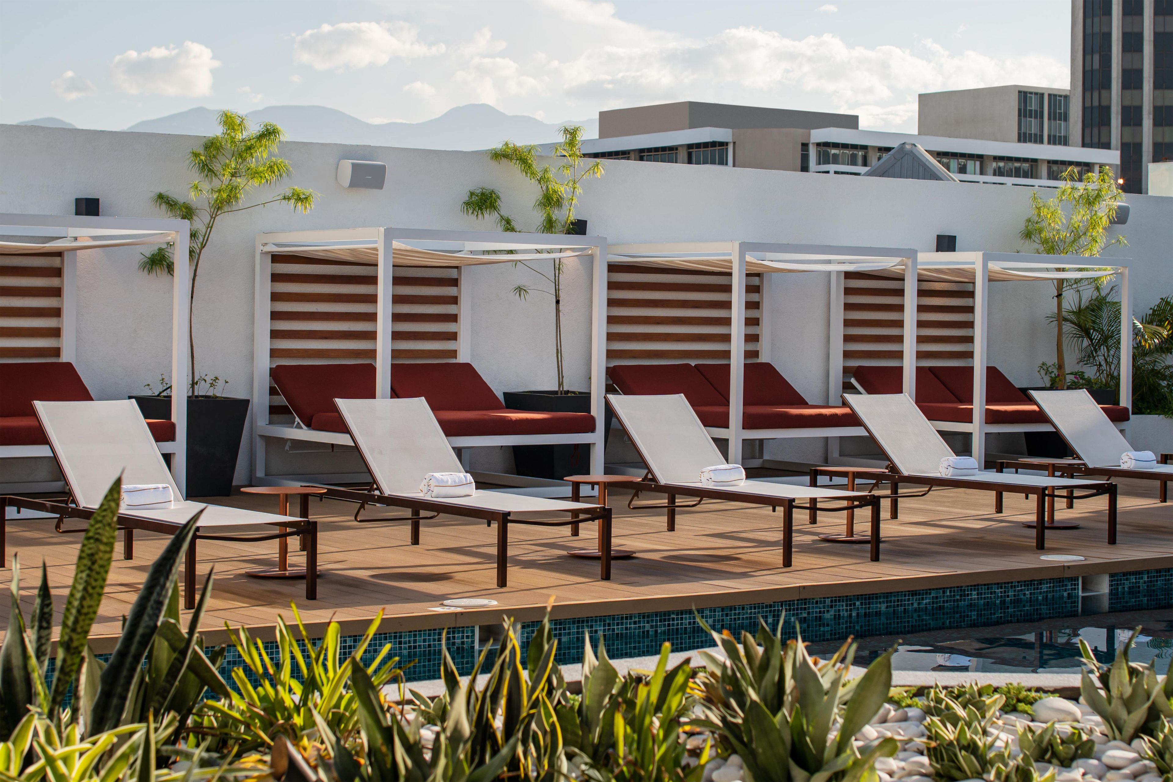 A rooftop pool area with sun loungers and a pool.
