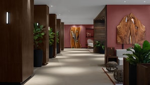 A modern hotel lobby with a wooden reception desk, seating area, and large wall art.