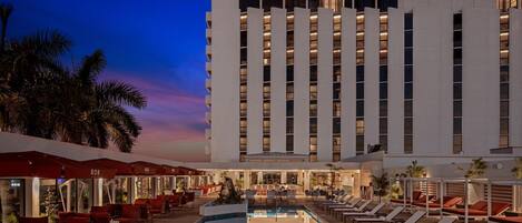 Un hotel con piscina, zona de estar al aire libre y un bar.