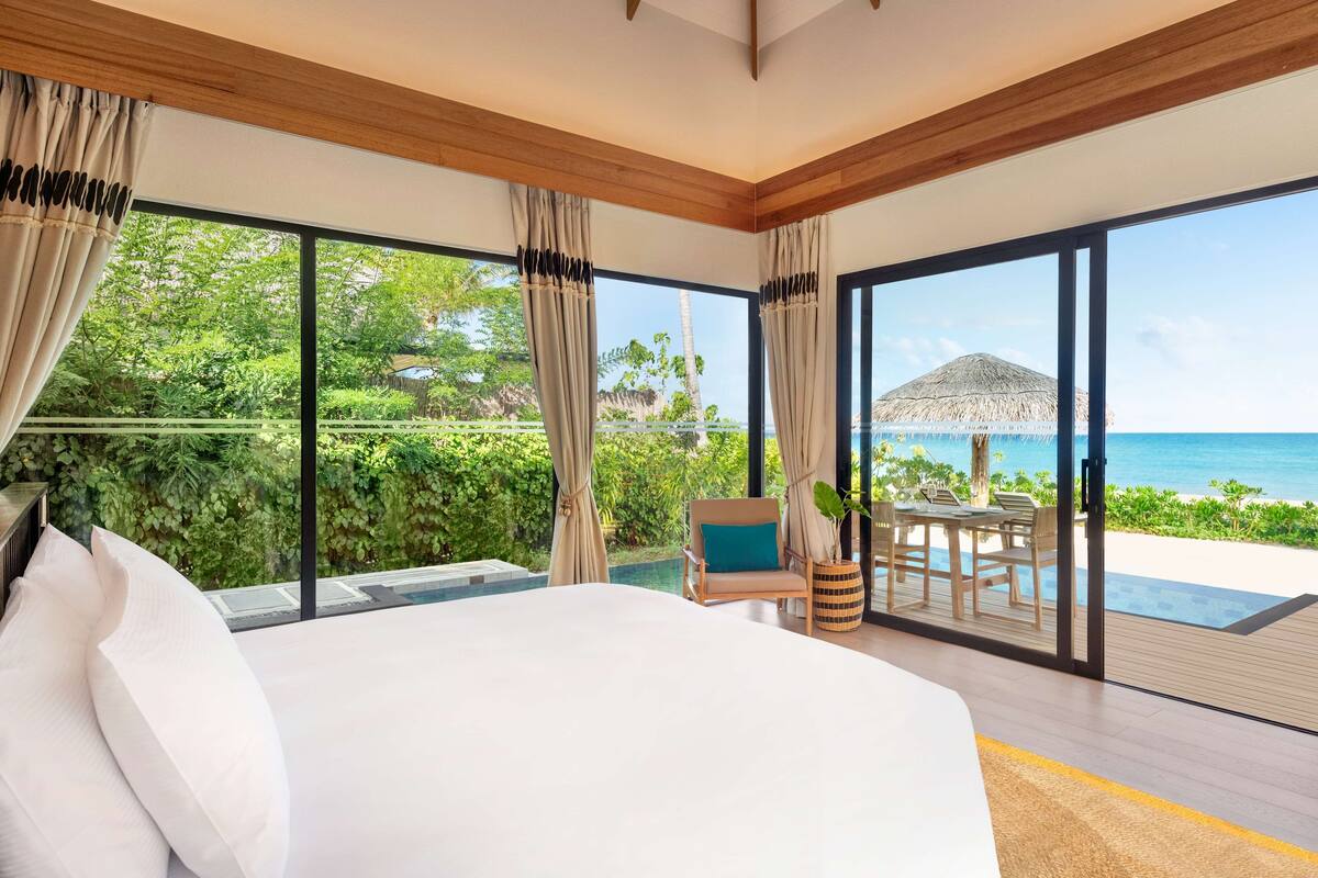 Ein Schlafzimmer mit einem großen Bett, Meerblick und einem Essbereich mit Tisch und Stühlen.