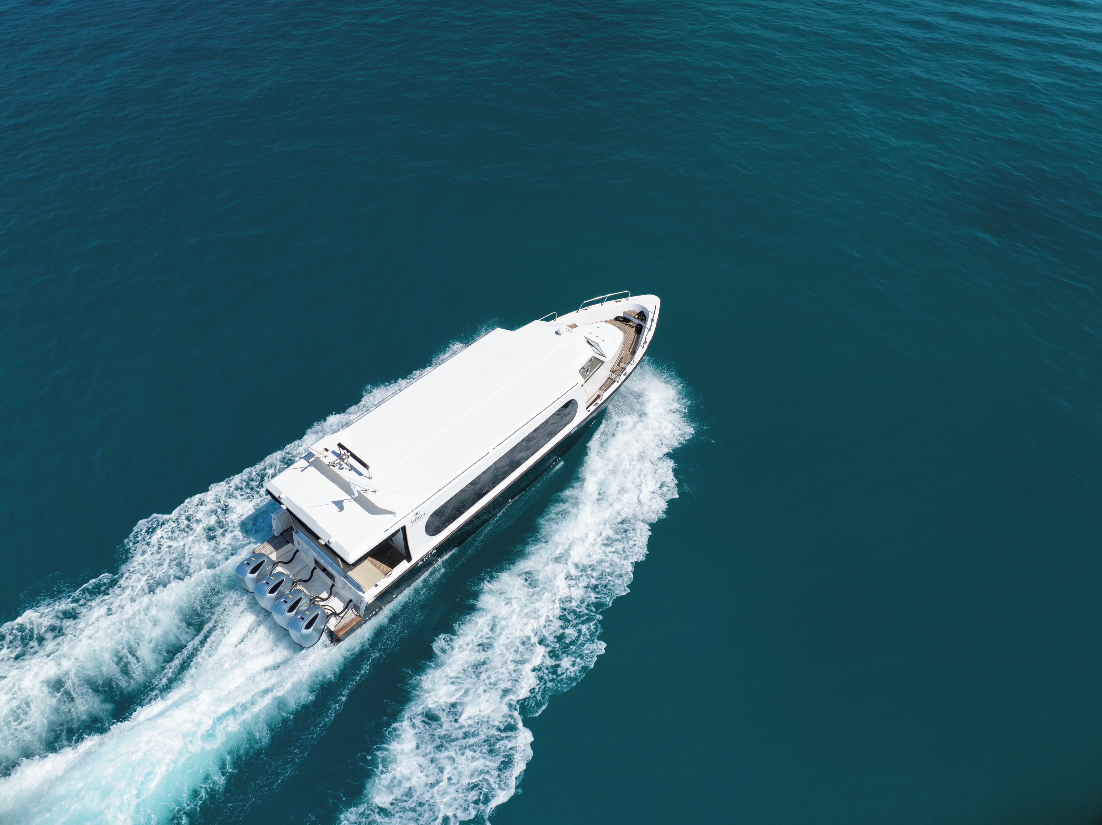 A high-speed boat cutting through calm blue waters.