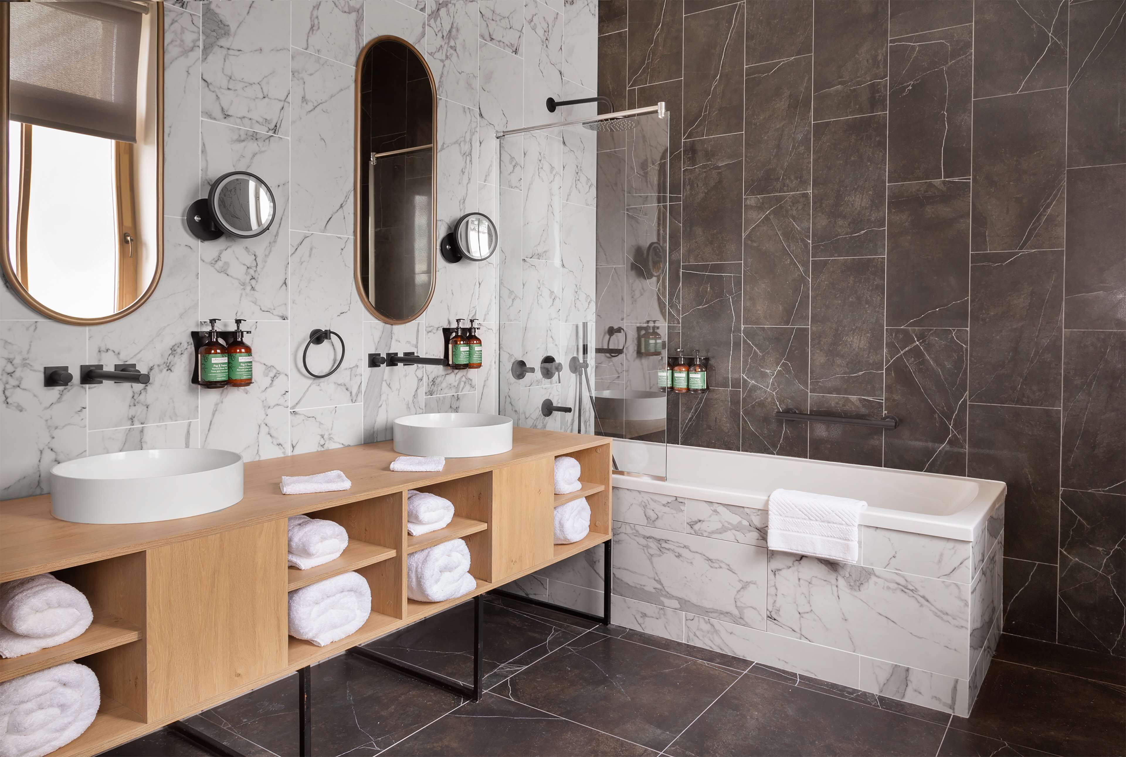 A modern bathroom with two sinks, a bathtub, and a shower.