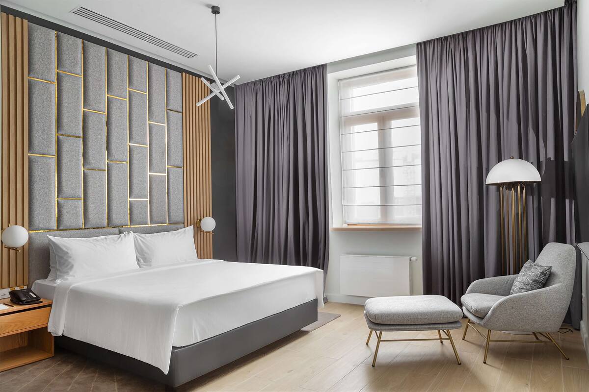 A modern bedroom with a large bed, a chair, and a desk.