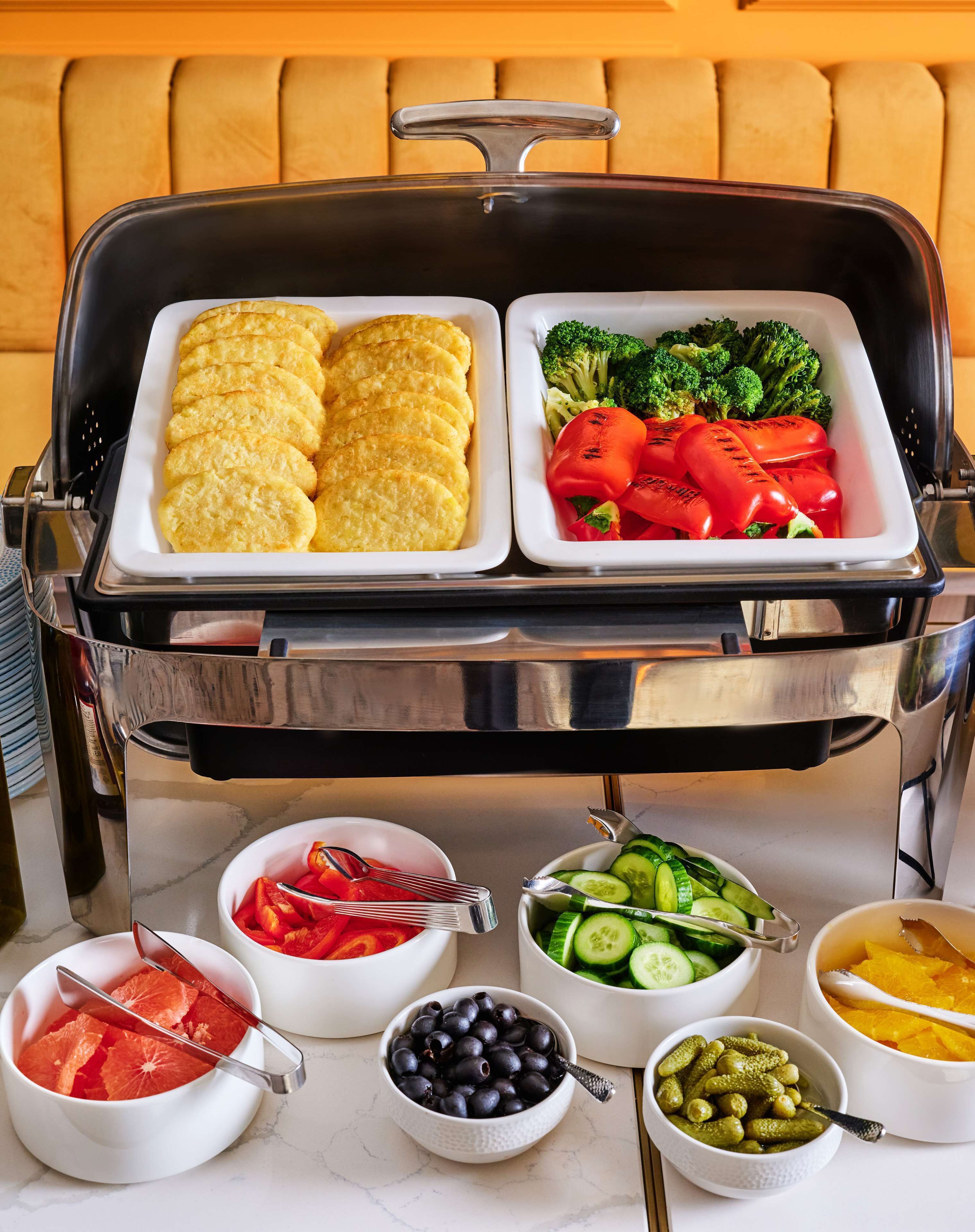 A buffet setup with various food items including bread, vegetables, and fruits.