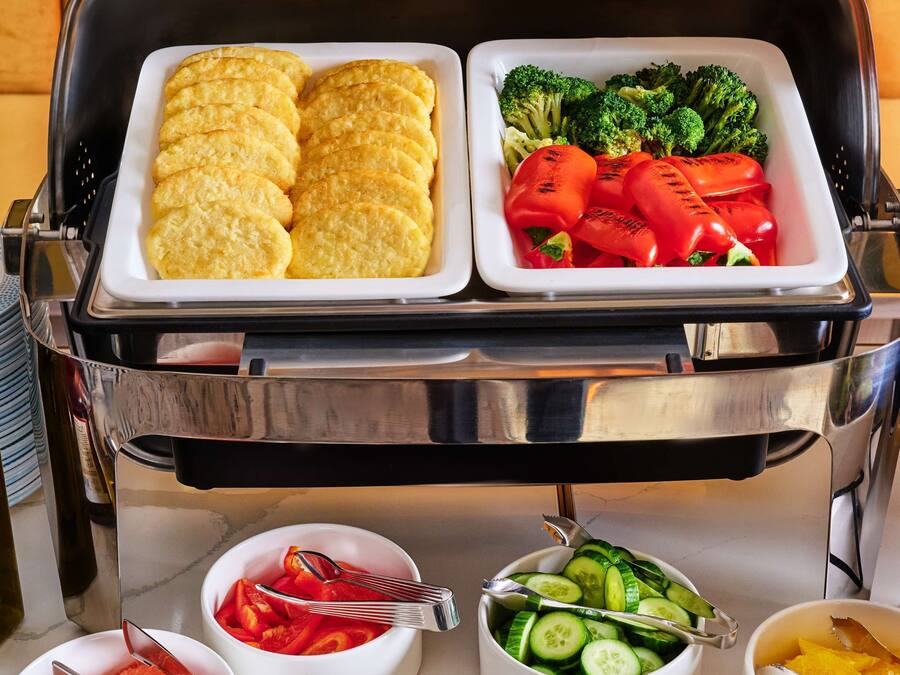 A buffet setup with various food items including bread, vegetables, and fruits.