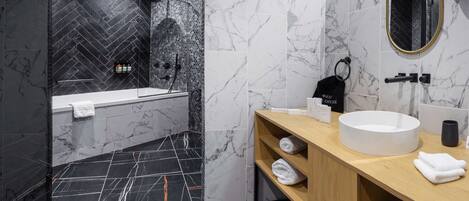 Un baño moderno con diseño de mármol blanco y negro, una bañera, un lavamanos y un espejo.