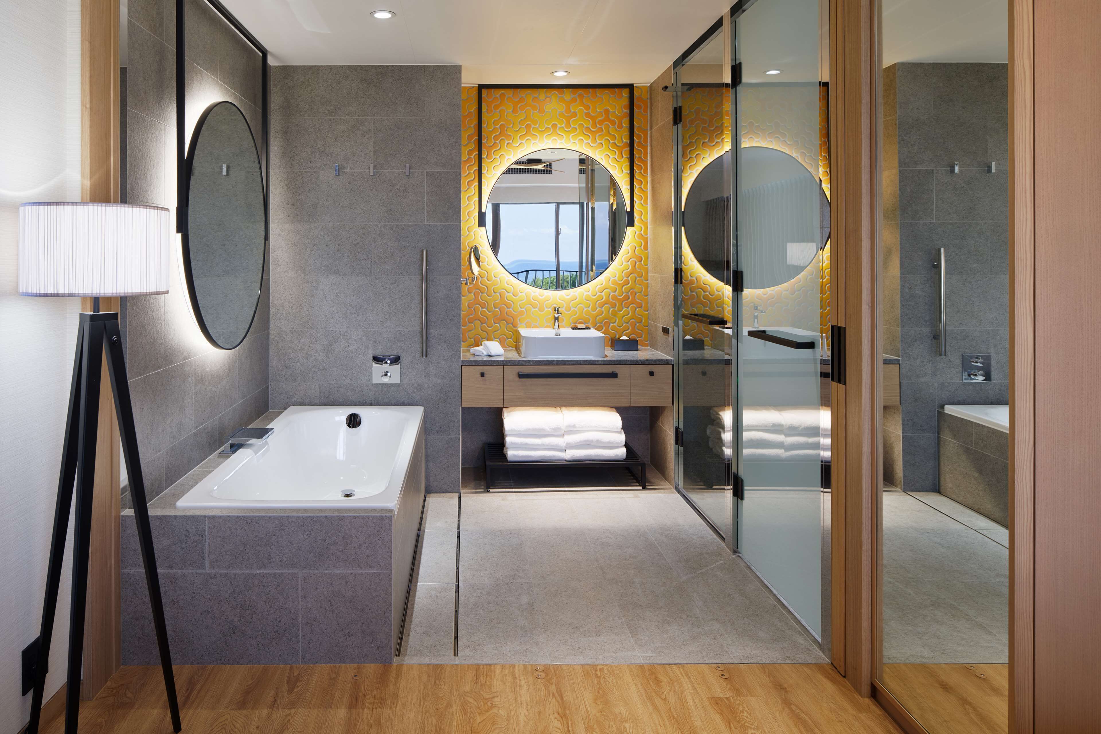 A modern bathroom with a large bathtub, a vanity with a mirror, and a shower area.