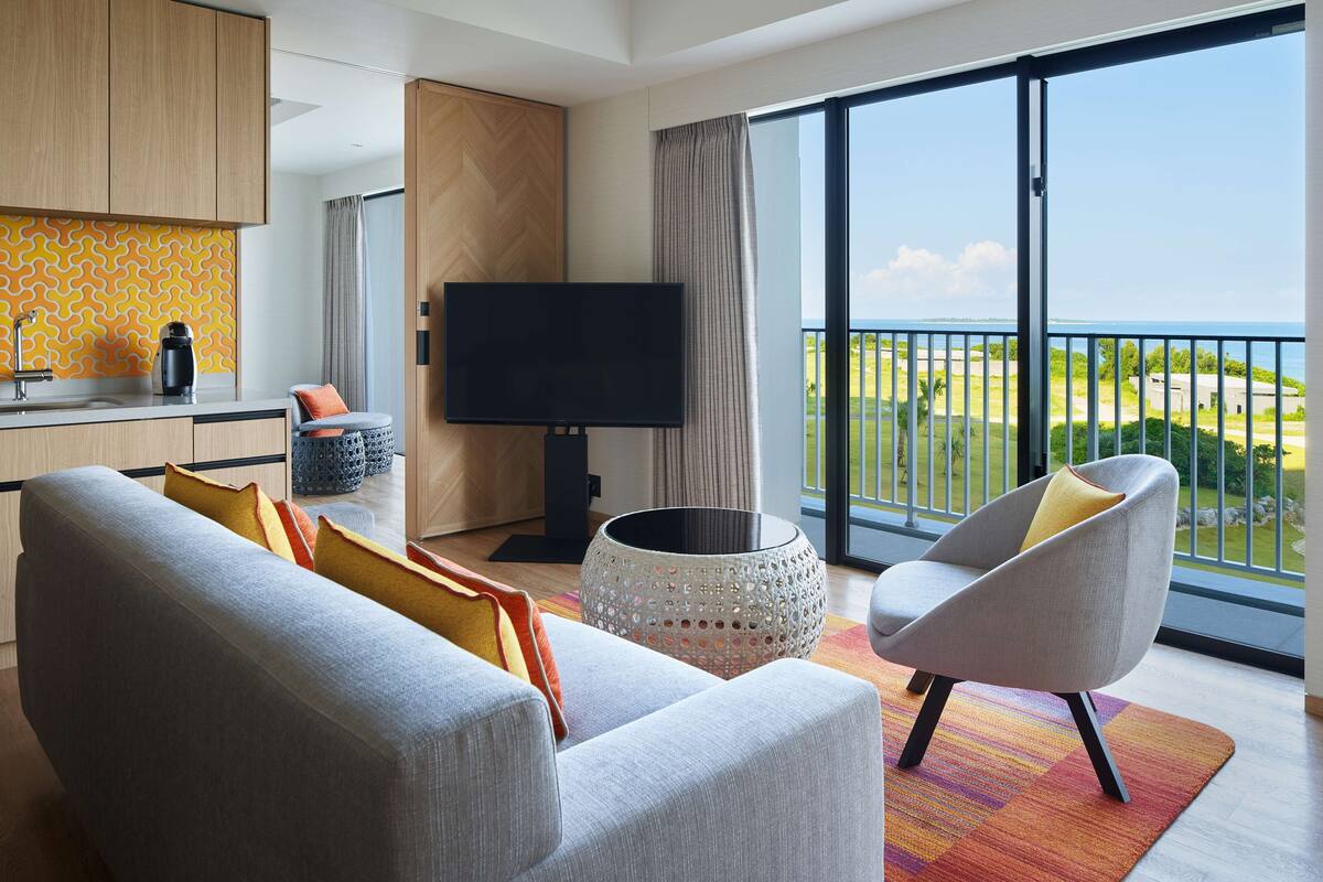 Ein modernes Wohnzimmer mit einer Couch, einem Fernseher und Blick ins Freie.