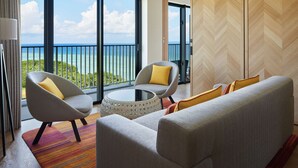 Een moderne hotelkamer met balkon, een bank, twee fauteuils en een salontafel.
