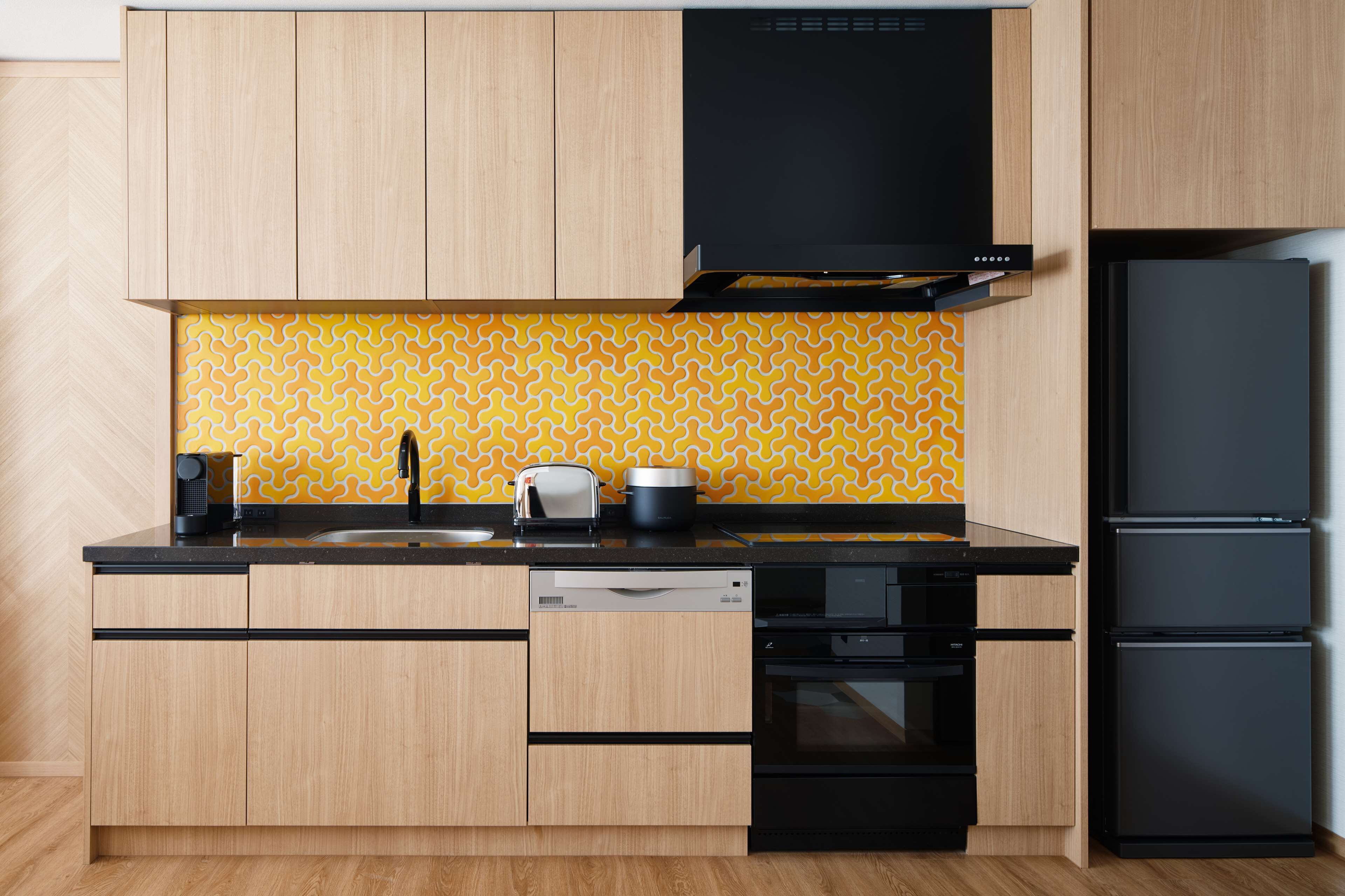 Eine moderne Küche mit Holzschränken, einem schwarzen Geschirrspüler, einem schwarzen Backofen und einem schwarzen Kühlschrank.