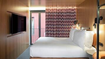 A hotel room with a large bed, a flat-screen TV mounted on the wall, and a patterned curtain.