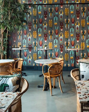 A restaurant interior with round tables, wicker chairs, and a patterned wall. - Se Catedral Hotel Porto, Tapestry Collection By Hilton (Porto)