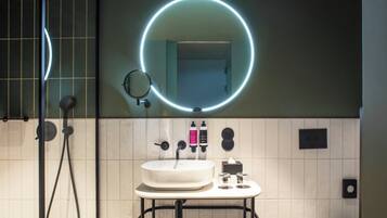 Un baño moderno con un espejo redondo, un lavamanos y una ducha.