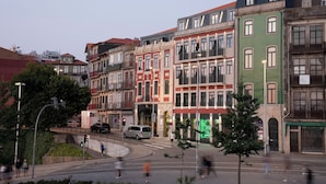 A row of multi-story buildings with balconies, a pedestrian crossing, and a street with cars and pedestrians. - Se Catedral Hotel Porto, Tapestry Collection By Hilton (Porto)