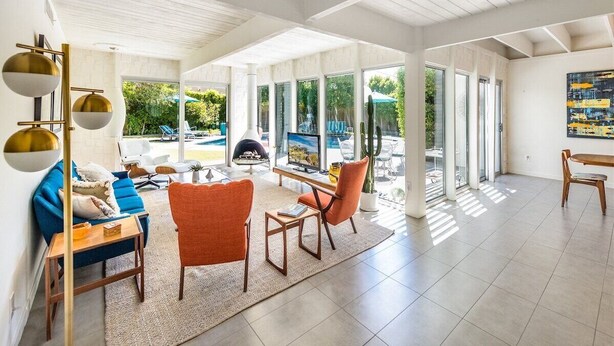Un'ampia zona giorno con vista piscina, arredi moderni e ampie finestre.