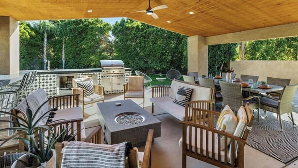 Une terrasse extérieure équipée d’un barbecue, d’un espace salon et d’un foyer.