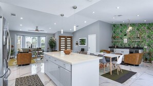 Une cuisine moderne dotée d’un îlot central, d’un coin repas avec des chaises et d’un espace de vie comprenant un canapé et une table basse.
