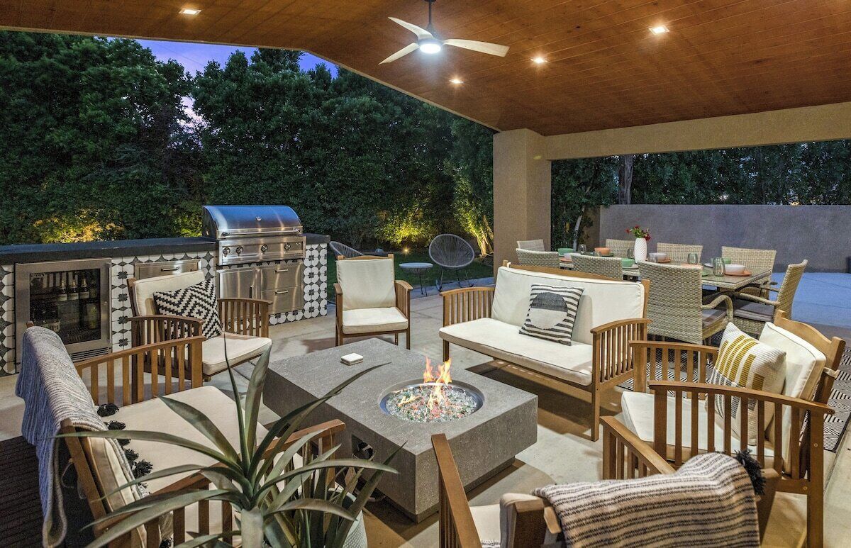 An outdoor patio with a grill, seating area, and fire pit.