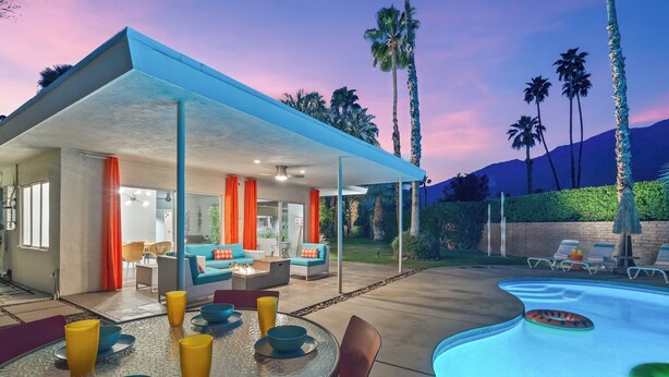 Un espace de vie extérieur moderne doté d’une piscine, d’un patio couvert et de coins salon.
