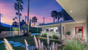 Une maison moderne dotée d’une piscine, de palmiers et d’une pelouse bien entretenue.