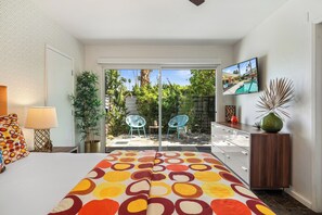 Ein Schlafzimmer mit Bett, Fernseher, Schreibtisch und Blick auf den Garten.