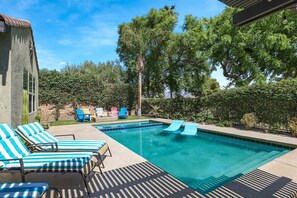 Une piscine avec des chaises longues et un espace patio.