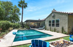 Un jardin avec une piscine, un espace salon extérieur et un foyer.