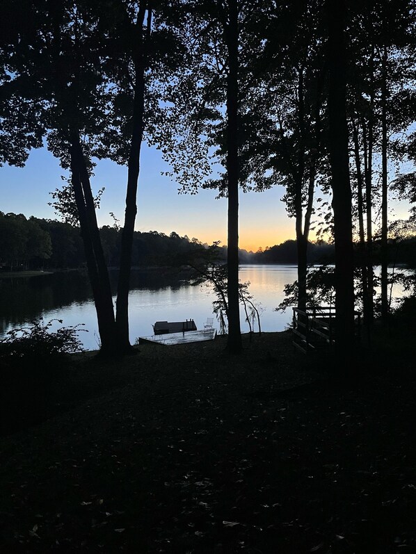 A lakeside view with trees and a dock.