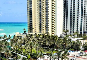 A high-rise hotel with multiple balconies overlooking a beach.