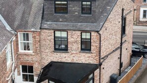 A modern two-story house with a brick facade, large windows, and a small attached garage. - Escape 2 Unwind At The Parade, Accommodates 10 (York)