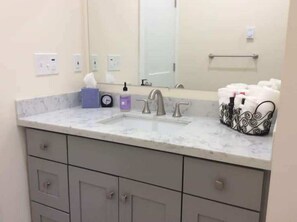 Un baño con lavamanos de mármol, un espejo y un perchero para toallas.