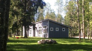 A single-story building with a flat roof, surrounded by a well-maintained lawn and tall trees. - Whidbey Island Orchard House Estate Langley, WA (Langley)