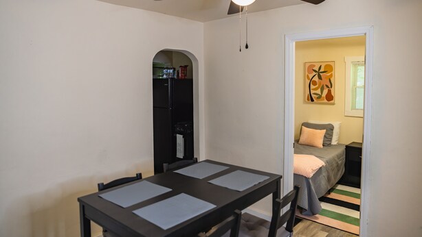 A dining area with a table and chairs, a ceiling fan, and a kitchen visible through an archway. - Close to Everything in Louisville!!! (Louisville)