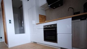 A modern kitchen with white cabinetry, a built-in oven, and a dishwasher. - Seagull's nest in the Villa Medici (Norderney)