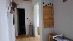A narrow hallway with wooden beams, a small bench, and a bed with a patterned cover. - Seagull's nest in the Villa Medici (Norderney)