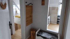 A room with a wooden bench, a small wooden cabinet, and a mirror on the wall. - Seagull's nest in the Villa Medici (Norderney)
