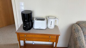 Ein kleiner Holztisch mit einer Kaffeemaschine, einem Toaster und einem Wasserkocher.