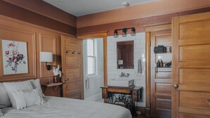 Une chambre à coucher avec un grand lit, une commode, une coiffeuse avec un miroir et une armoire en bois.