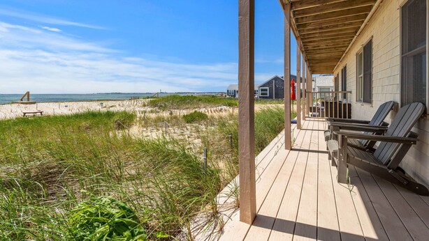 A wooden deck with a view of the beach and dunes.