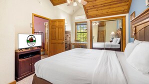 Ein Schlafzimmer mit einem großen Bett, Holzboden, einem Fernseher, einem Schreibtisch und einem Fenster.