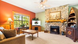 Ein gemütliches Wohnzimmer mit Kamin aus Stein, einem Fernseher und einer komfortablen Sitzecke.